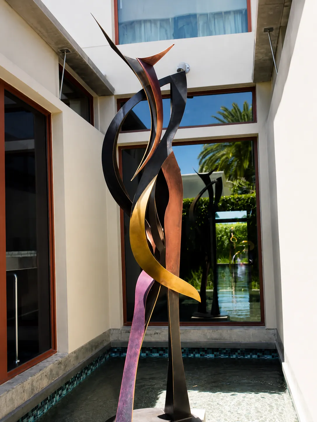 Monumental metal sculpture installed in a modern courtyard.